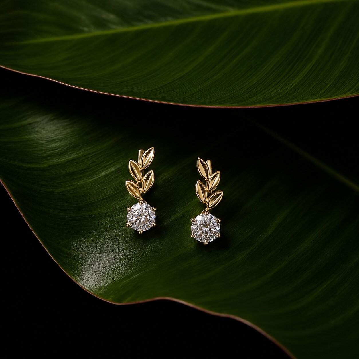 Botanical diamond earrings in gold with leaf-inspired design on tropical green leaf backdrop