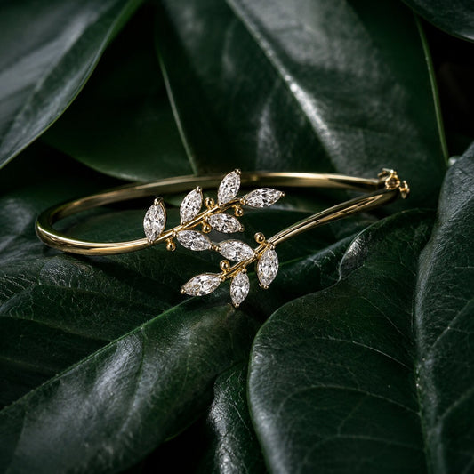 Nature-inspired diamond bracelet in gold with leaf motif on dark green tropical leaves