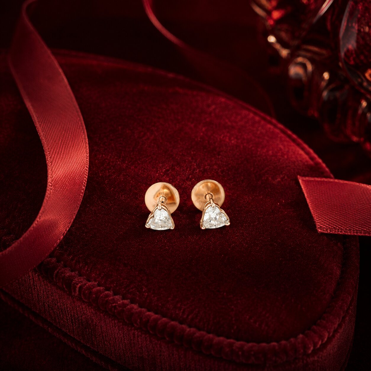 Luxury trillion diamond stud earrings on crimson velvet flat lay
