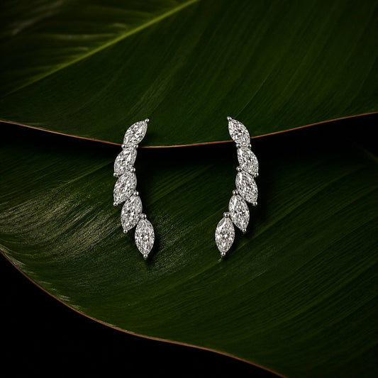 Marquise diamond drop earrings with botanical leaf-inspired design on tropical green leaf backdrop